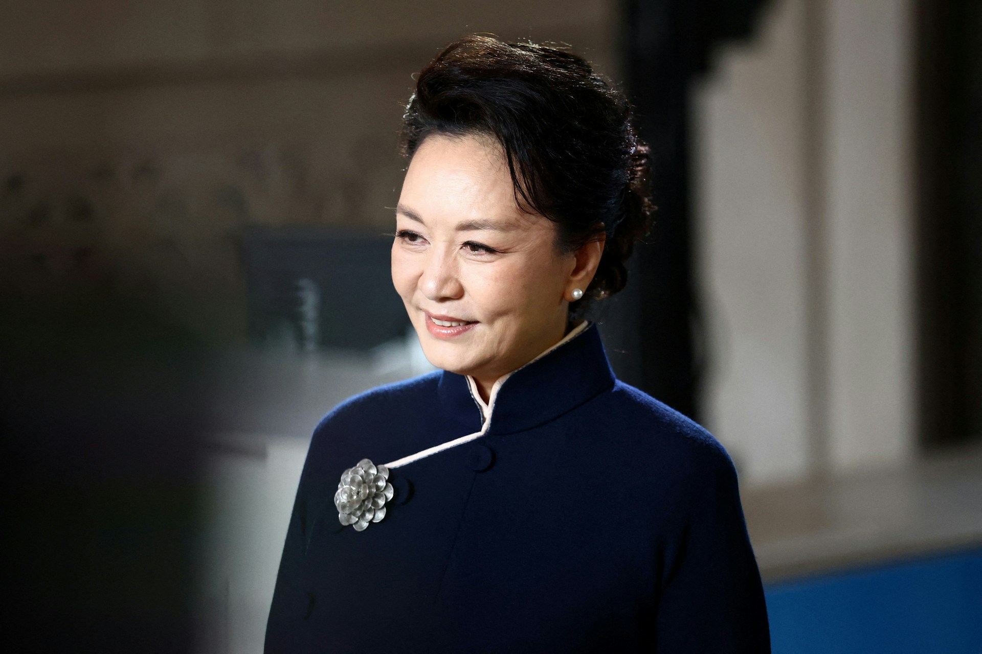 【习近平访美】彭丽媛则穿著深蓝色、高立领的旗袍式洋装,别上一枚银色花卉胸针。(路透社)