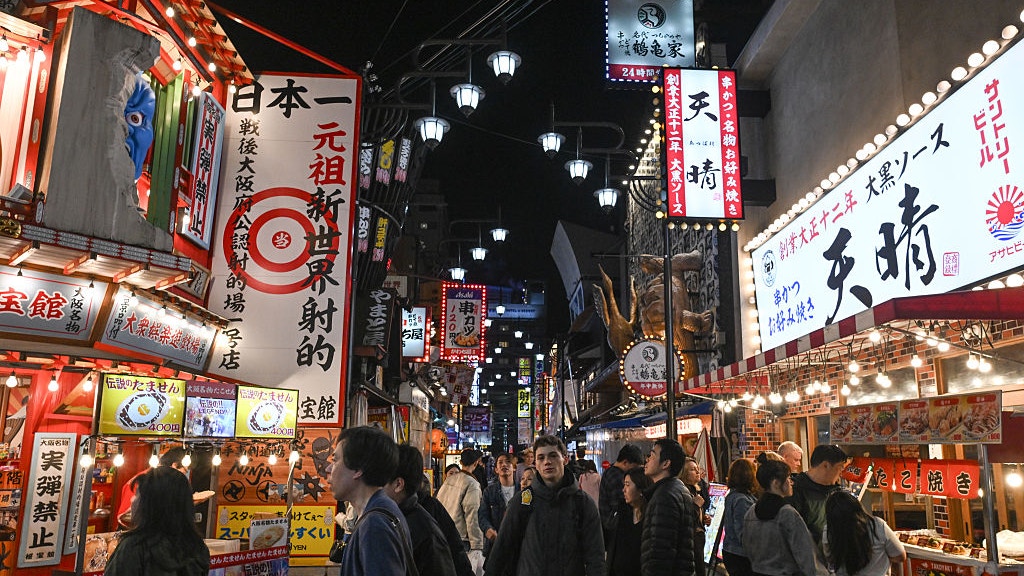 2026年4月4日,游客和当地居民挤在日本大阪的小巷中,巷两旁排列著传统餐厅的招牌。(Getty Images)