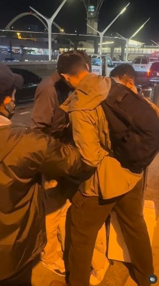 一名在现场自报姓名为「Jing Zhao」的华人女子,在机场航站楼外被多名便衣人员控制并带上一辆白色厢型车。面对旁人的追问,现场人员确认自己属于美国移民与海关执法局(ICE),并称带走女子的原因是「违反移民规定」。(IG@veganchefchristucker影片截图)