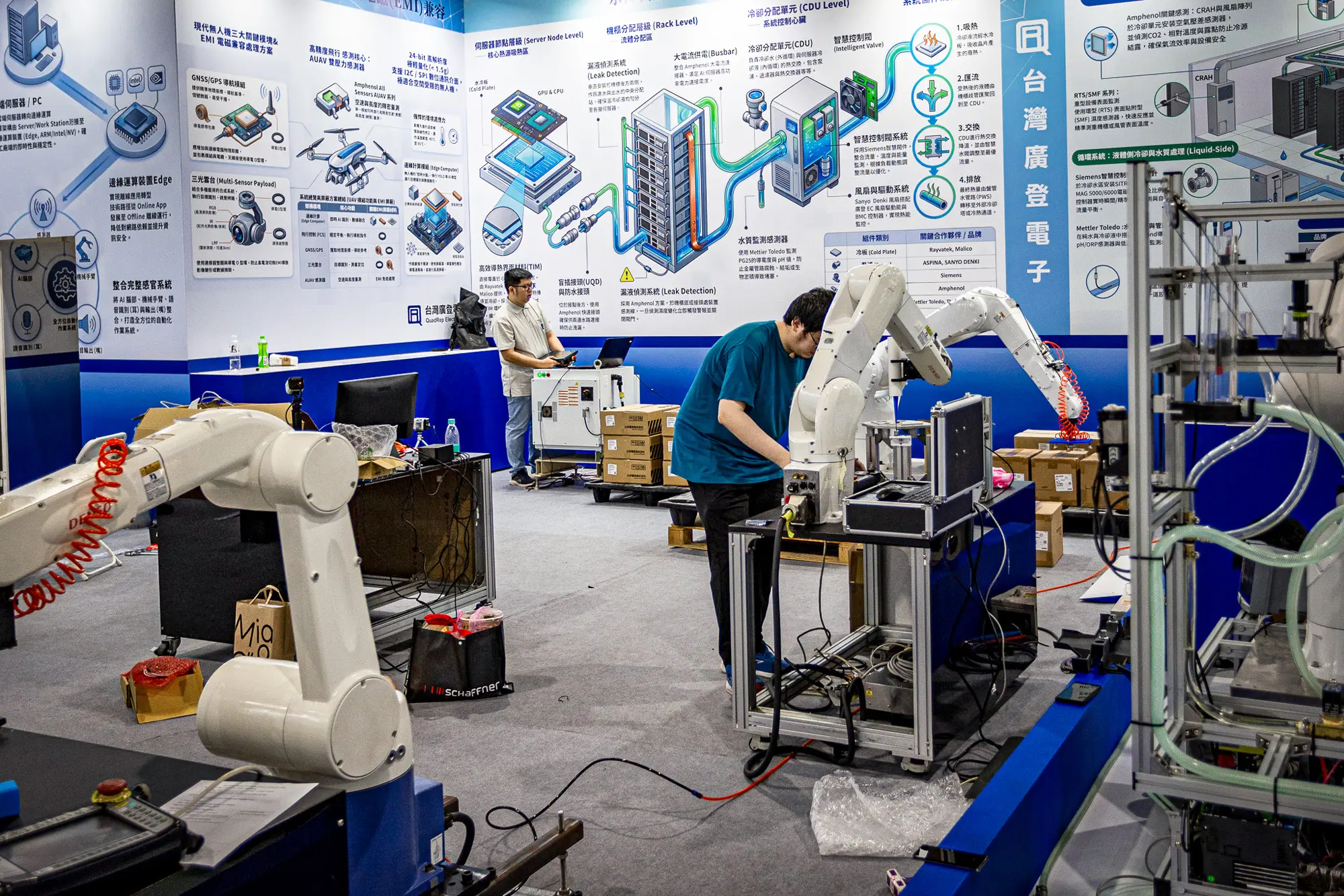 2026年6月1日,在台湾台北举行的COMPUTEX国际电脑展前夕,工程师们正在展位上配置和测试工业机器人手臂。COMPUTEX是全球规模最大的年度计算机及科技贸易展之一,主要展示下一代人工智能芯片、机器人技术和计算基础设施等。(Cheng Chia Huang/Getty Images)
