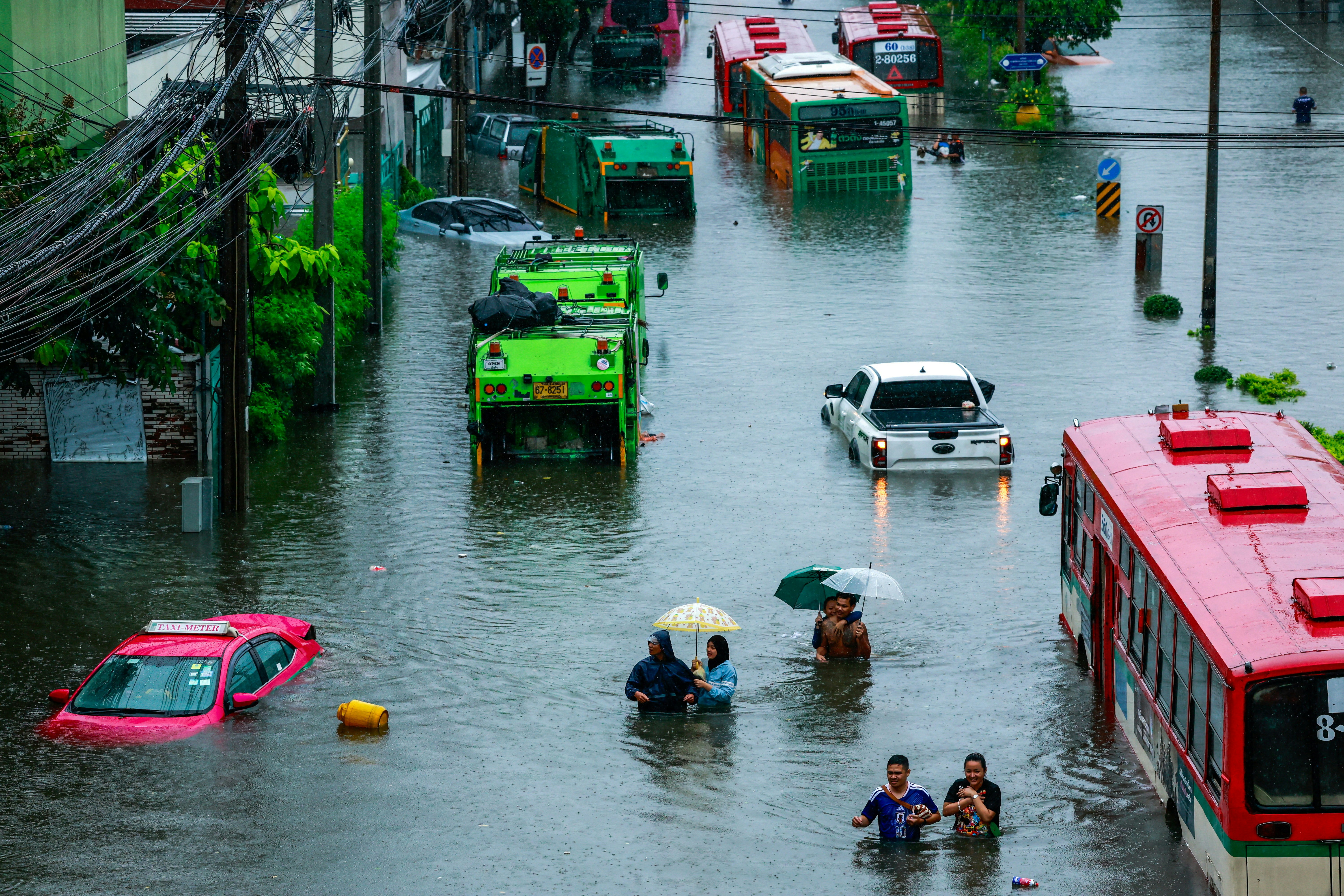 2026年9月26日,泰国曼谷,行人趟过暴雨中被洪水淹没的街道。(Reuters)