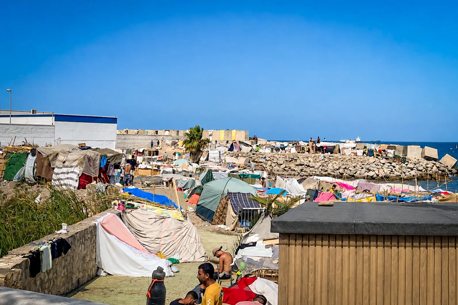 2026年9月19日，西班牙休达的贝尼特斯海滩（Playa de Benítez）上挤满了临时搭建的帐篷。当局将部分人员转移至港口一处可容纳1,700人的新营地后，仍有超过2,000人无处安置。（Etienne Fauchaire／英文大纪元）