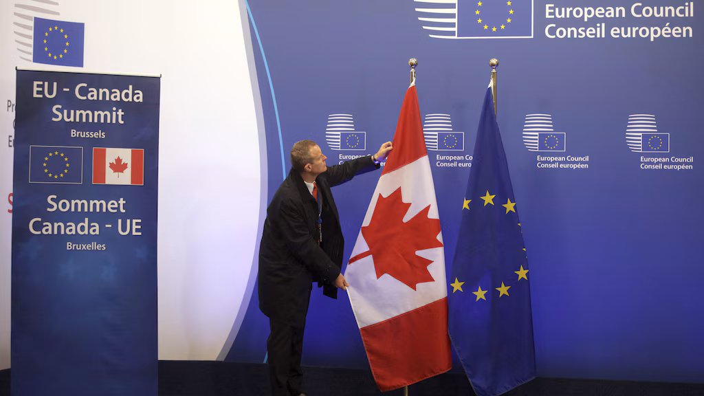 A member of protocol adjusts the EU and Canadian flags prior to an EU-Canada summit at the European Council building in Brussels, Sunday, Oct. 30, 2016. Canadian and EU officials, in a one-day summit, are to sign the Comprehensive Economic and Trade Agreement (CETA). (AP Photo/Olivier Matthys)