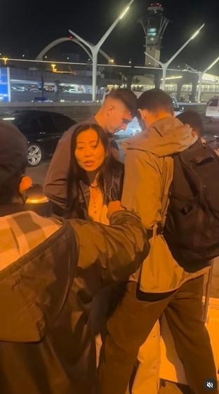 一名在现场自报姓名为「Jing Zhao」的华人女子,在机场航站楼外被多名便衣人员控制并带上一辆白色厢型车。面对旁人的追问,现场人员确认自己属于美国移民与海关执法局(ICE),并称带走女子的原因是「违反移民规定」。(IG@veganchefchristucker影片截图)