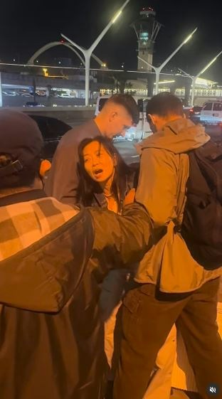 一名在现场自报姓名为「Jing Zhao」的华人女子,在机场航站楼外被多名便衣人员控制并带上一辆白色厢型车。面对旁人的追问,现场人员确认自己属于美国移民与海关执法局(ICE),并称带走女子的原因是「违反移民规定」。(IG@veganchefchristucker影片截图)