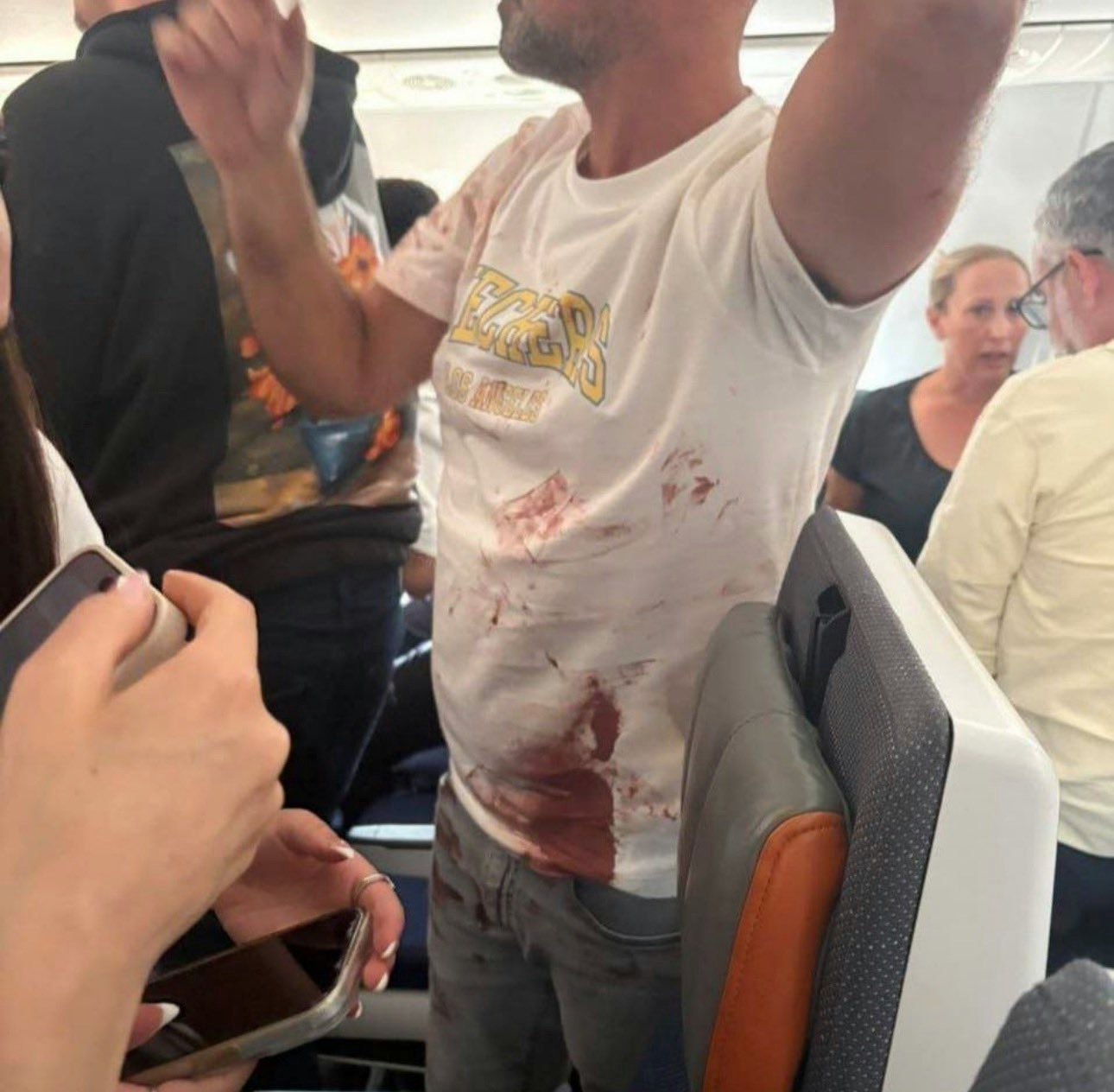 杜拜航空客机惊魂:事件中部份乘客协助制服施袭者,现场图片可见有乘客身上染血(影片截图)