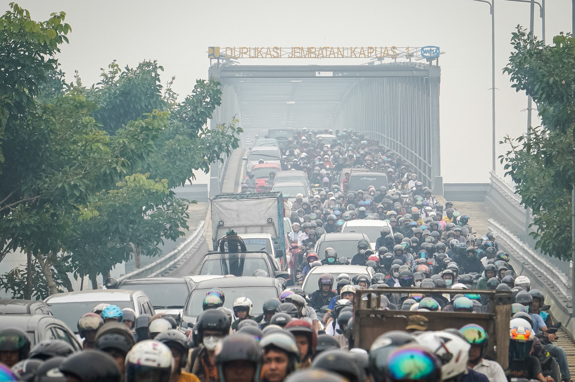 2026年10月7日,位于西加里曼丹省坤甸市(Pontianak)的卡普阿斯第一大桥复线桥(Duplikasi Jembatan Kapuas 1)笼罩在一片烟霾之中,许多民众戴著口罩经过此地。(Dito/AFP via Getty Images)