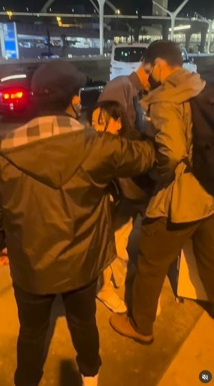 一名在现场自报姓名为「Jing Zhao」的华人女子,在机场航站楼外被多名便衣人员控制并带上一辆白色厢型车。面对旁人的追问,现场人员确认自己属于美国移民与海关执法局(ICE),并称带走女子的原因是「违反移民规定」。(IG@veganchefchristucker影片截图)