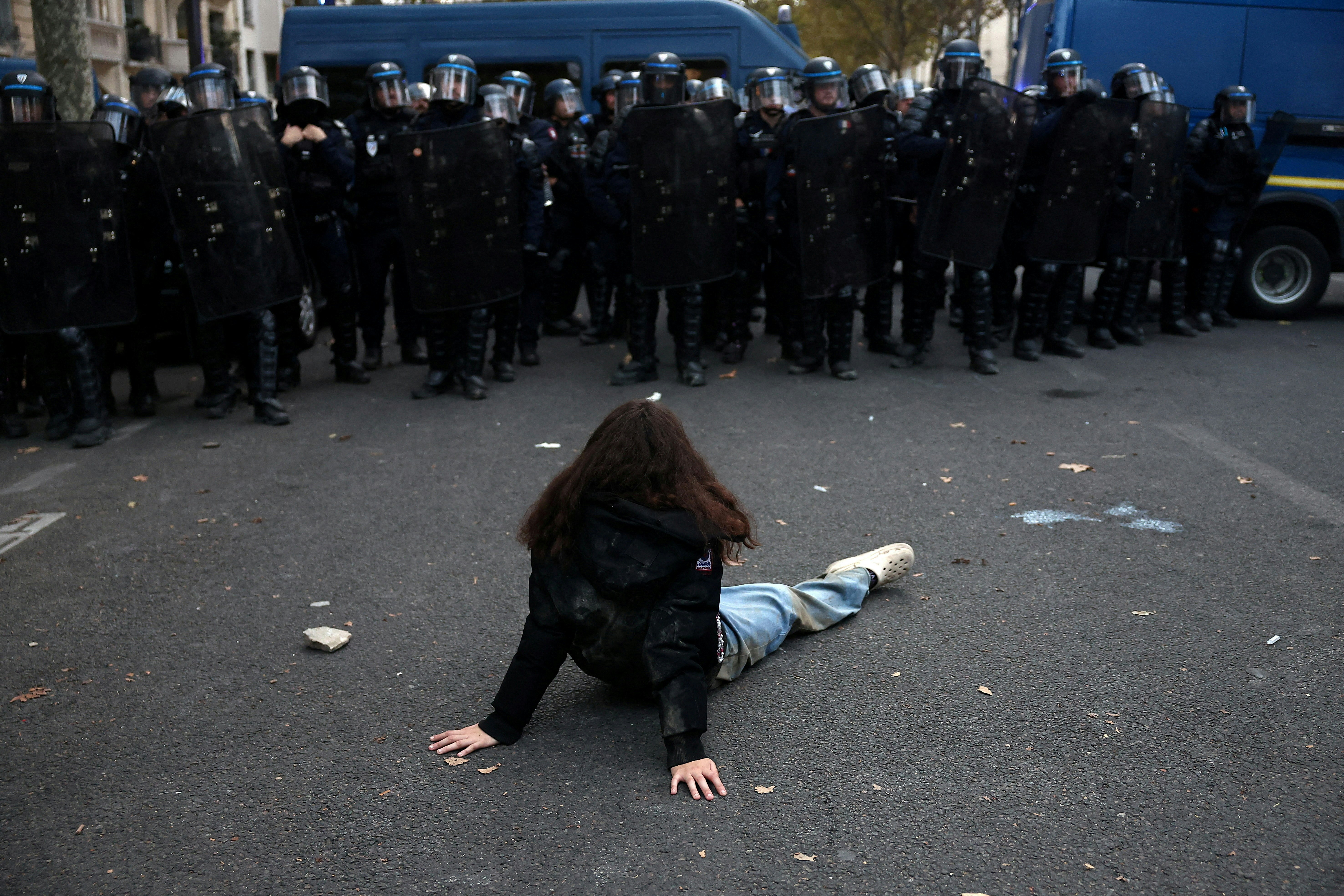 2026年10月13日,法国巴黎,一名示威者坐在地上,面对法国防暴警察。(Reuters)