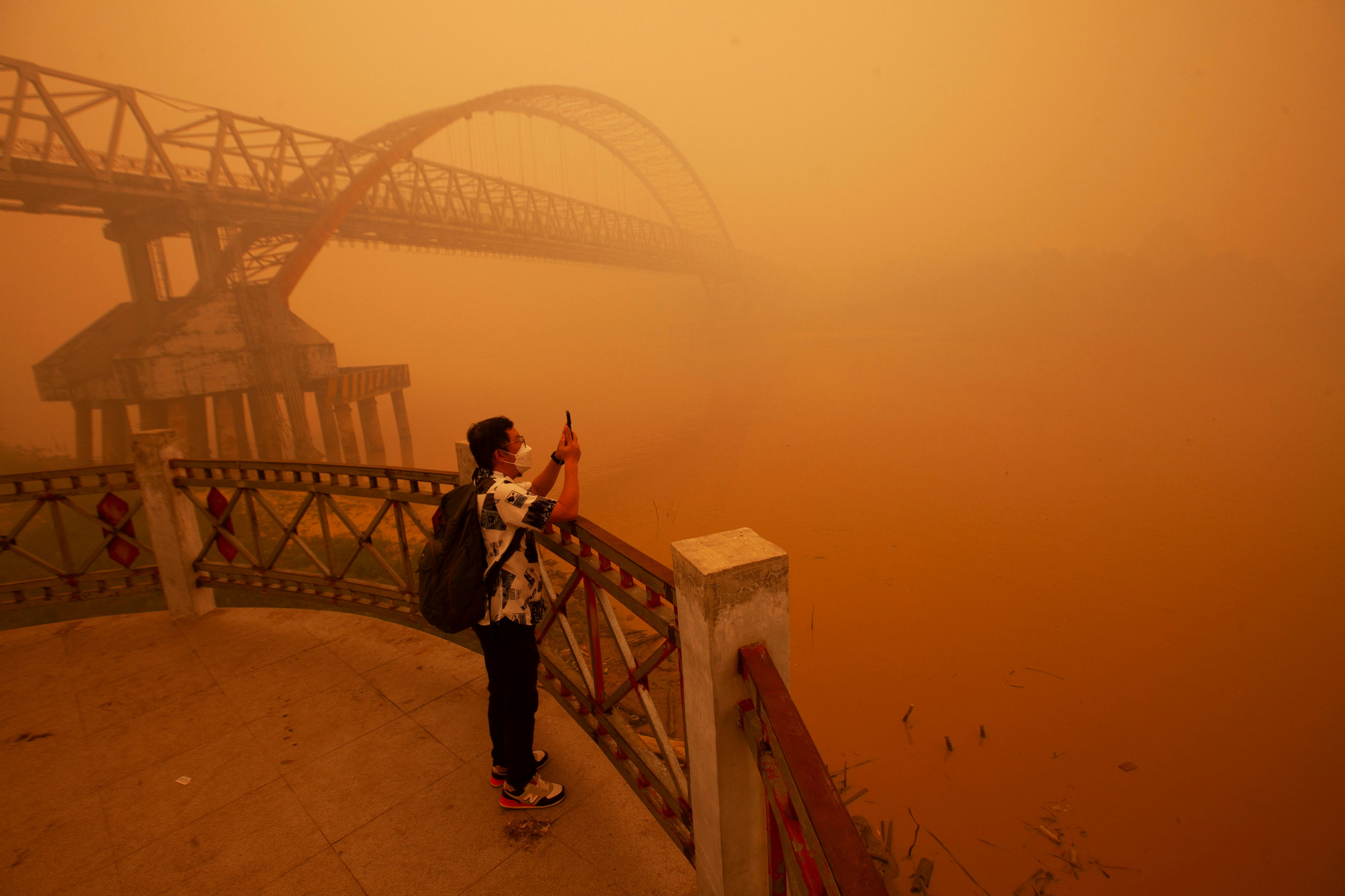 图为2026年10月14日,印尼中加里曼丹省(Central Kalimantan)首府帕朗卡拉亚(Palangka Raya)受山火产生的烟霾影响,天空变成一片橙色。有民众戴上口罩,于卡哈扬河(Kahayan River)旁边影相。(Reuters)