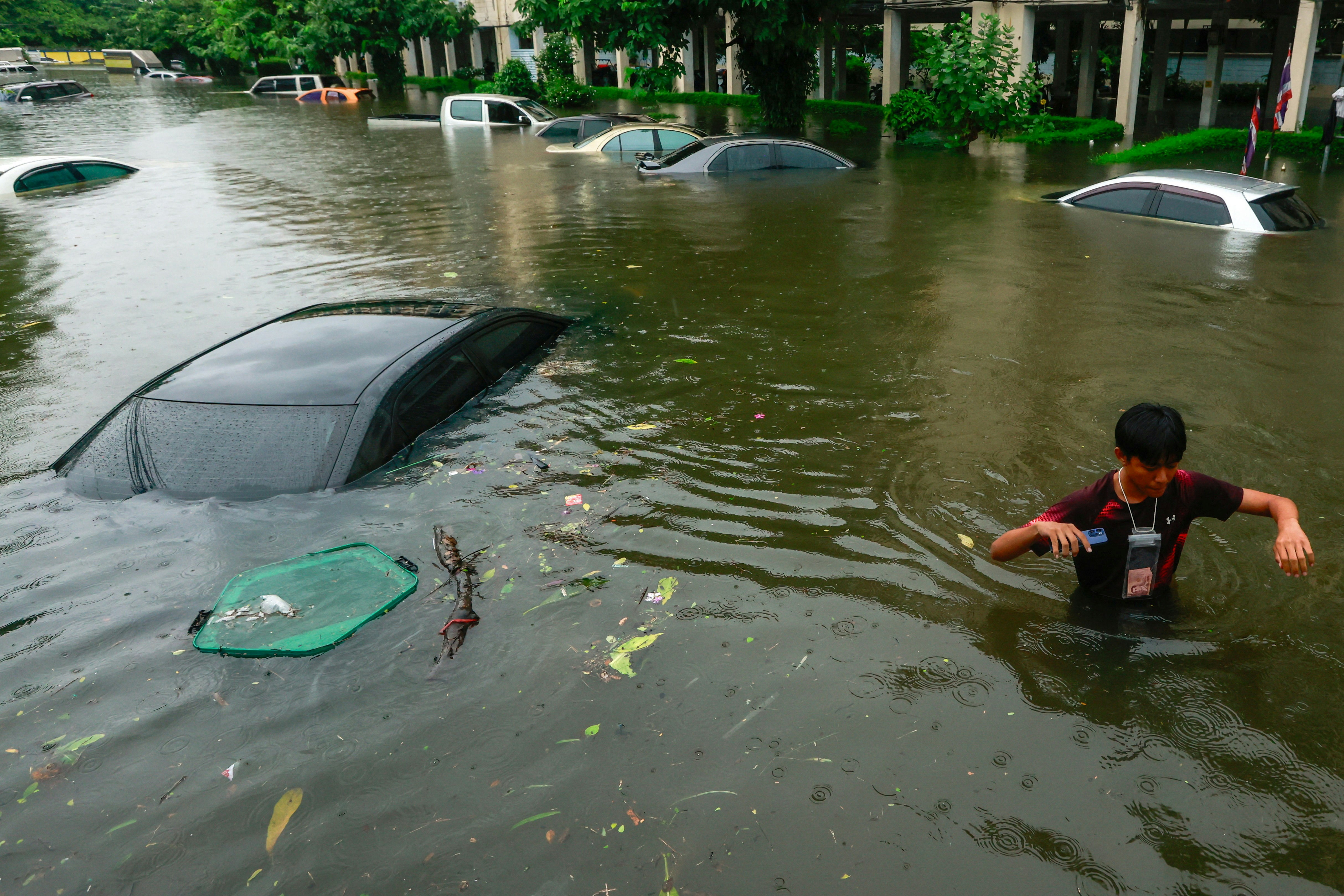 2026年9月26日,泰国曼谷,一名行人趟过暴雨中被洪水淹没的街道。(Reuters)