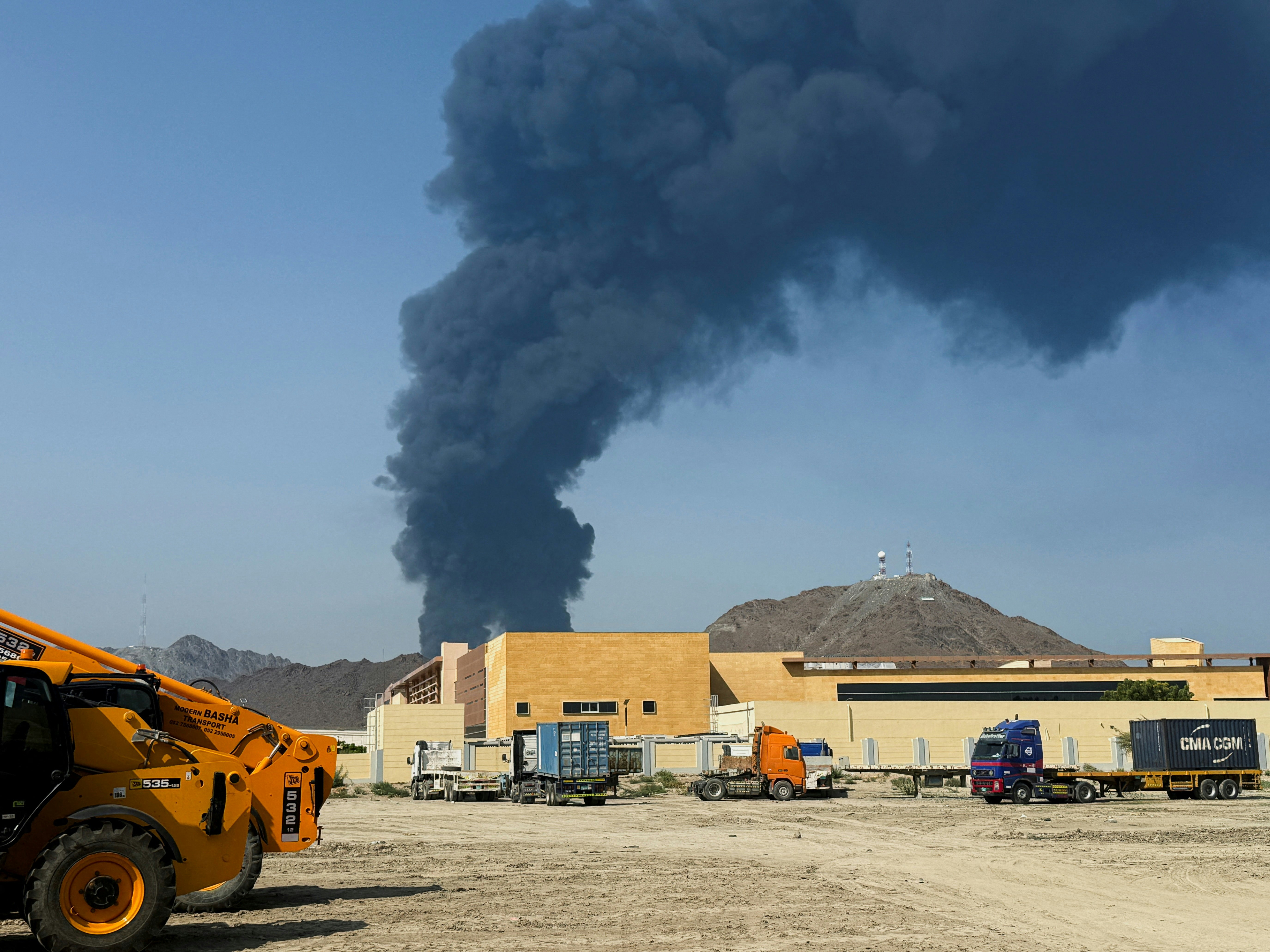 伊朗战争:图为2026年3月16日,阿联酋最大港口富查伊拉(Fujairah)石油工业区遭无人机袭击,拦截的残骸落在地上,并引起浓烟。(Reuters)