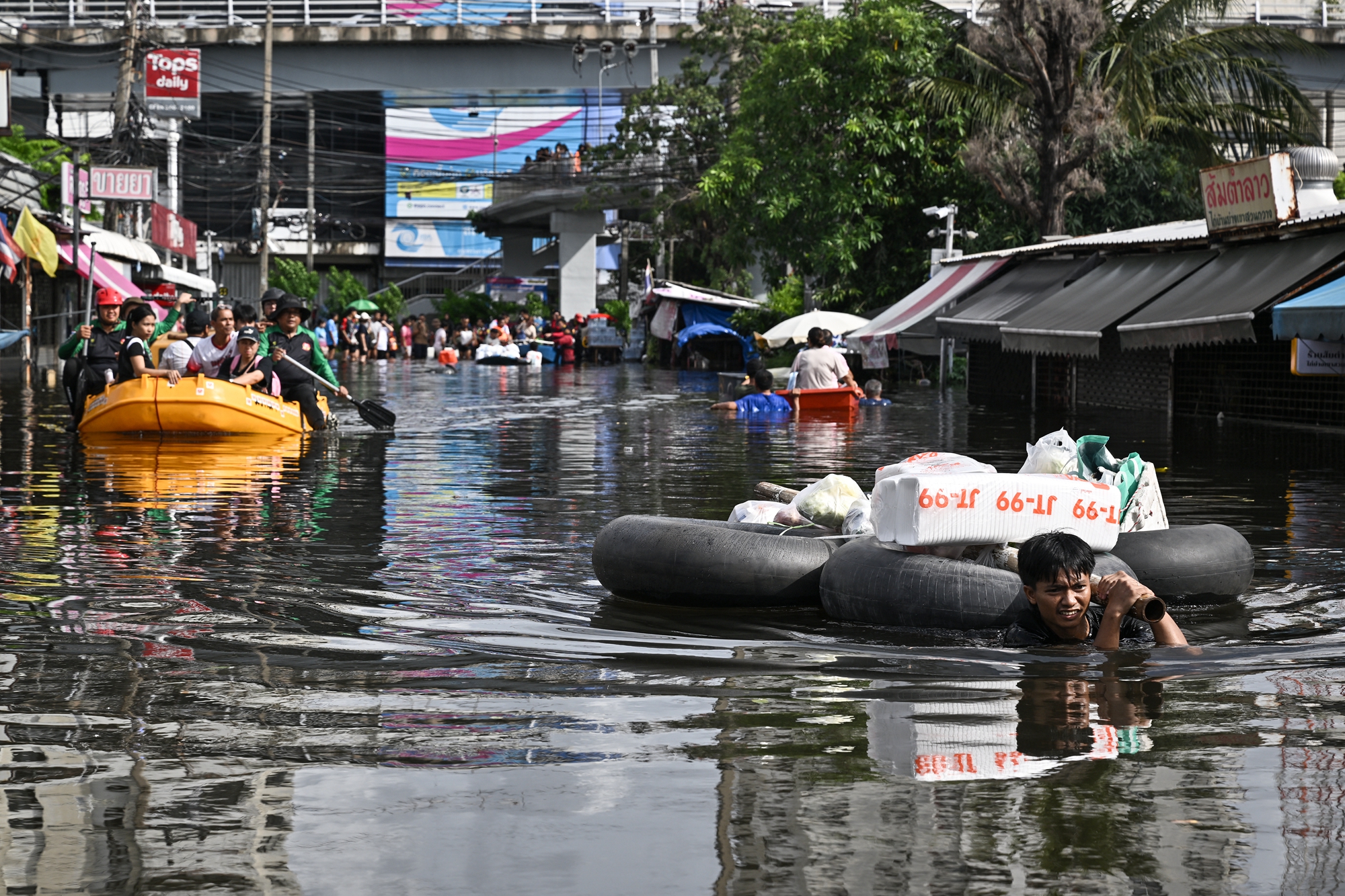 2026年9月28日,曼谷邦甲比区(Bang Kapi)一片汪洋,居民利用身边各种能浮于水上的工具出行或运载生活物资。(Lillian Suwanrumpha/AFP via Getty Images)