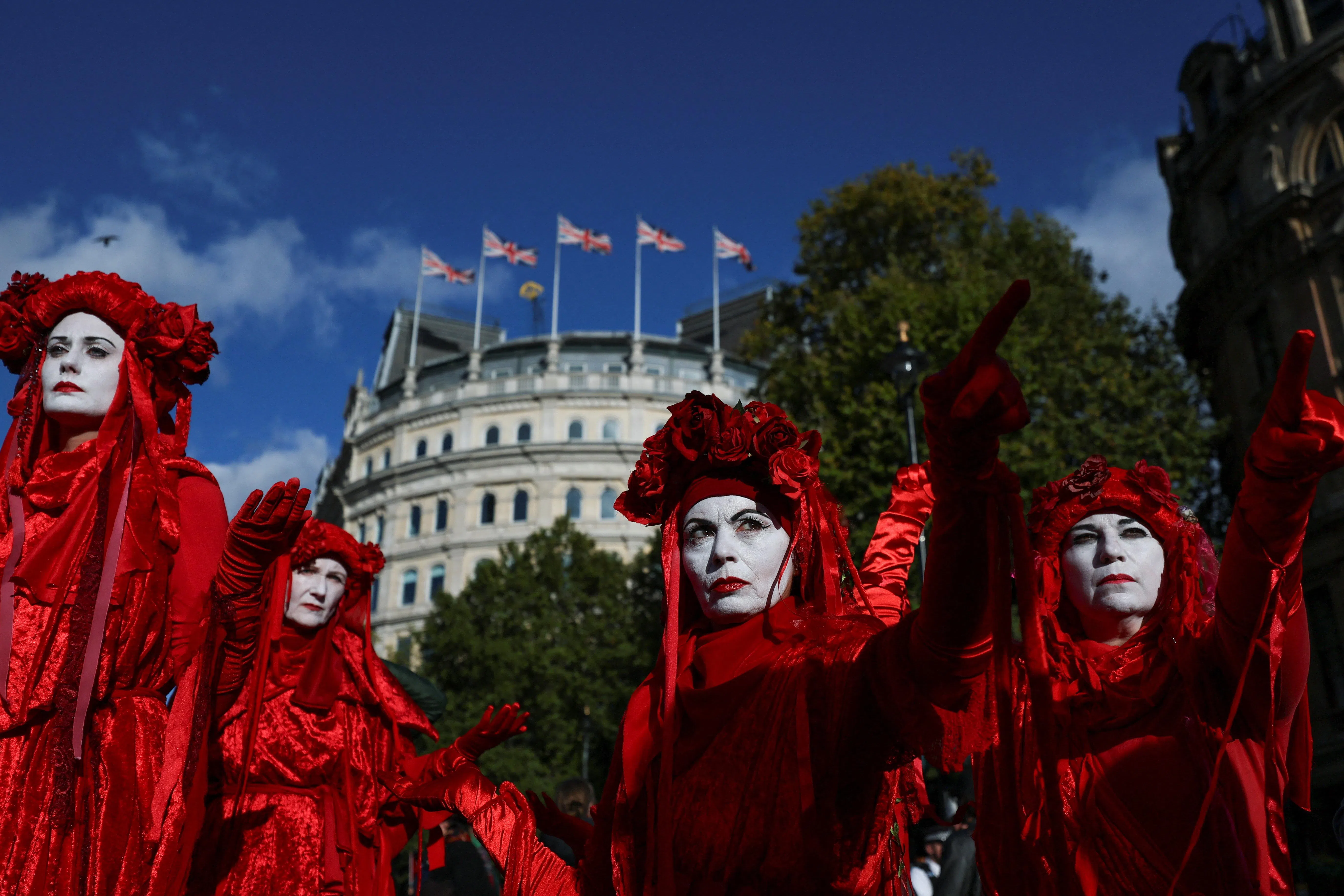 在英国伦敦特拉法加广场,行为艺术团体“红色叛军旅”(Red Rebel Brigade)的成员身穿红色服饰参与支持巴勒斯坦的抗议游行,以纪念加沙战争三周年。(路透社)