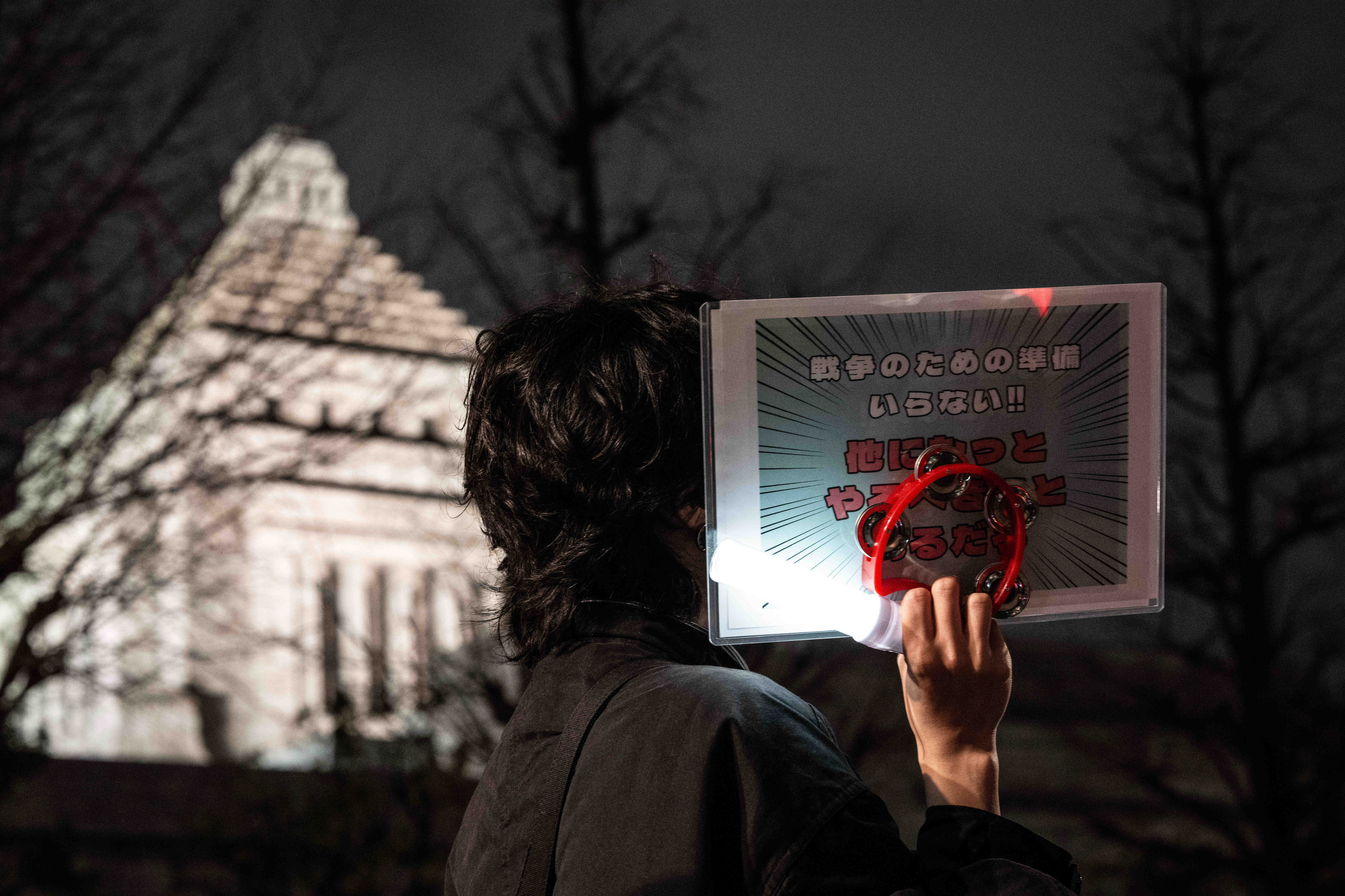 2月24日，在日本东京的众议院第二议员会馆前，民众手持标语参加抗议活动。新华社记者贾浩成摄