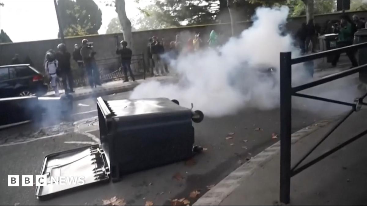 Riots on the streets of France with a bin on the floor with smoke behind it