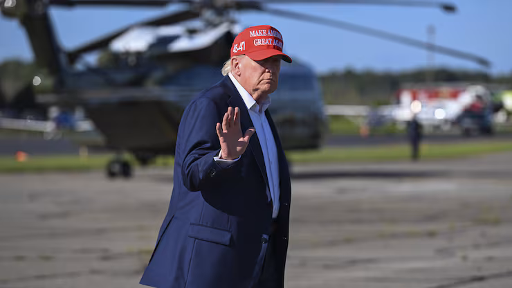 Le président Donald Trump sur le tarmac d'un aéroport portant une casquette.