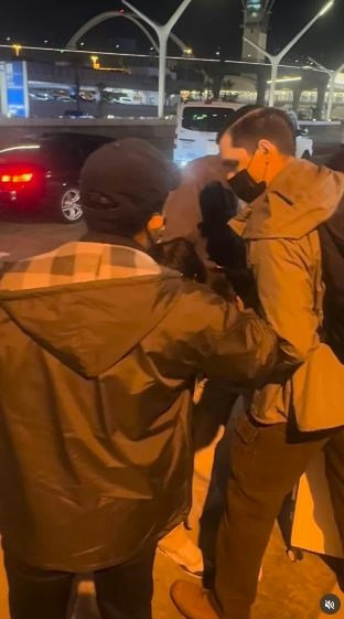 一名在现场自报姓名为「Jing Zhao」的华人女子,在机场航站楼外被多名便衣人员控制并带上一辆白色厢型车。面对旁人的追问,现场人员确认自己属于美国移民与海关执法局(ICE),并称带走女子的原因是「违反移民规定」。(IG@veganchefchristucker影片截图)