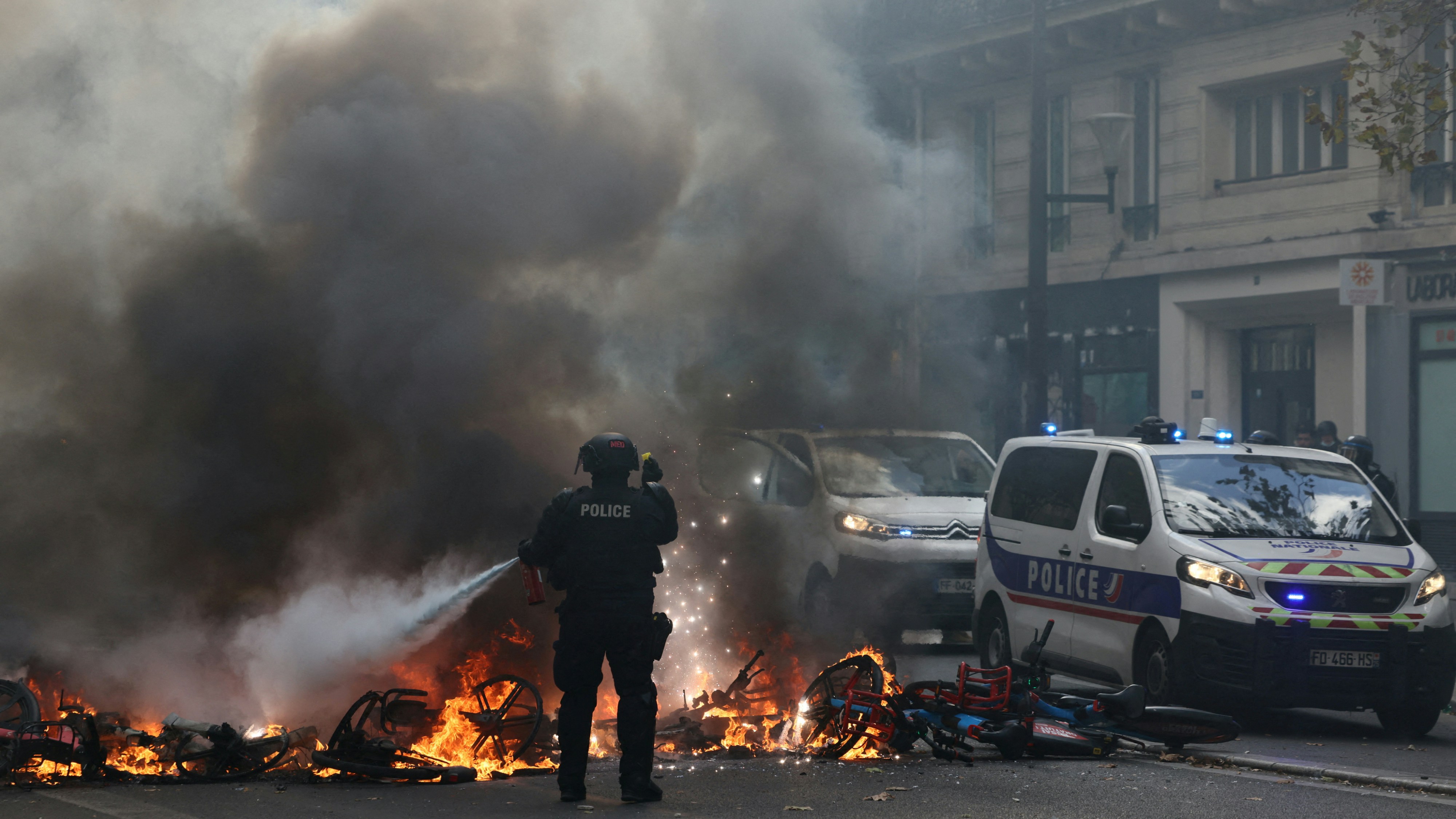 2026年10月17日,法国巴黎,一名法国警员尝试扑灭正在燃烧的自行车。当时,由「黄背心」运动发起的全国性抗议活动正在进行,旨在反对高昂的生活成本和不断上涨的燃料价格。(Reuters)